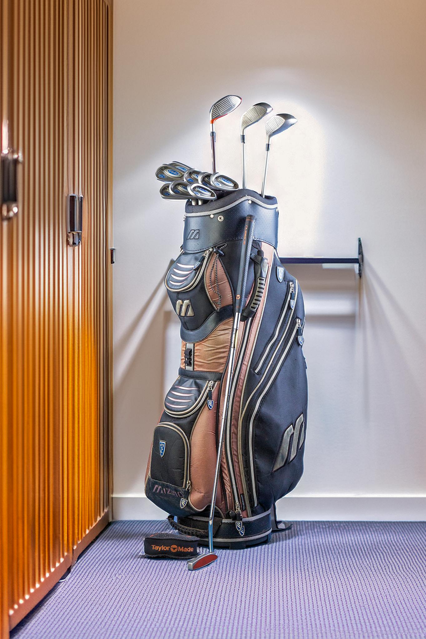 Golf equipment bag placed in a locker room setting, ideal for sports and leisure imagery.